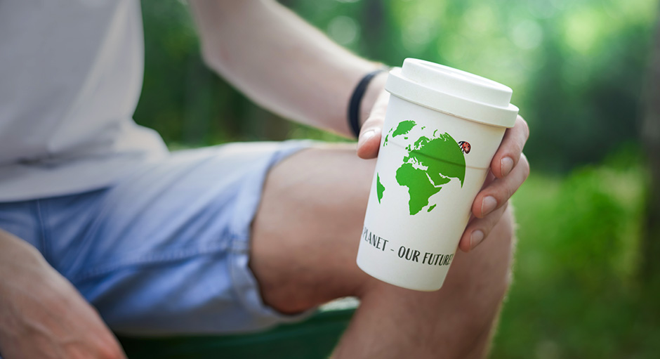 Mann hält einen Mehrwegbecher