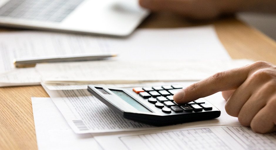 Taschenrechner mit Hand auf Schreibtisch