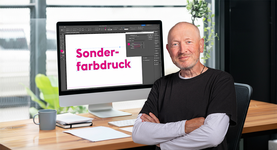 Andreas von FLYERALARM vor einem Bildschirm-Arbeitsplatz mit dem Wort: Sonderfarbdruck