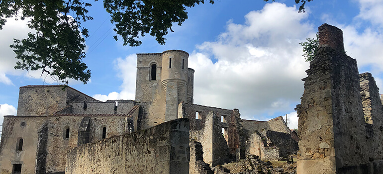 Blick auf eine historische Burganlage mit Türmen und Ruinen bei blauem Himmel.