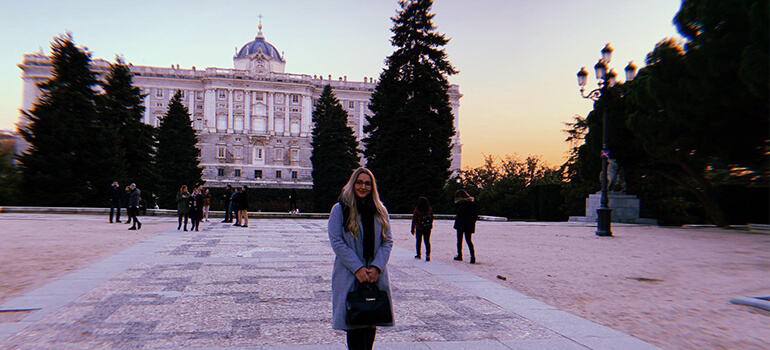 Blick auf den Königspalast von Madrid bei Sonnenuntergang, Menschen auf dem Platz.