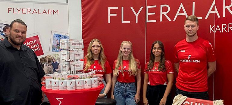 Das FLYERALARM Team am Messestand auf der vocatium 2023 mit Infomaterial und Werbeartikeln.