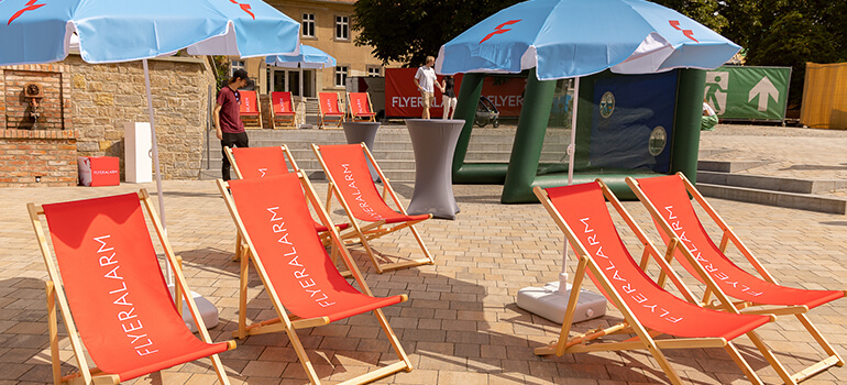 Liegestühle mit FLYERALARM-Aufdruck auf dem Außengelände des Sommerfests.